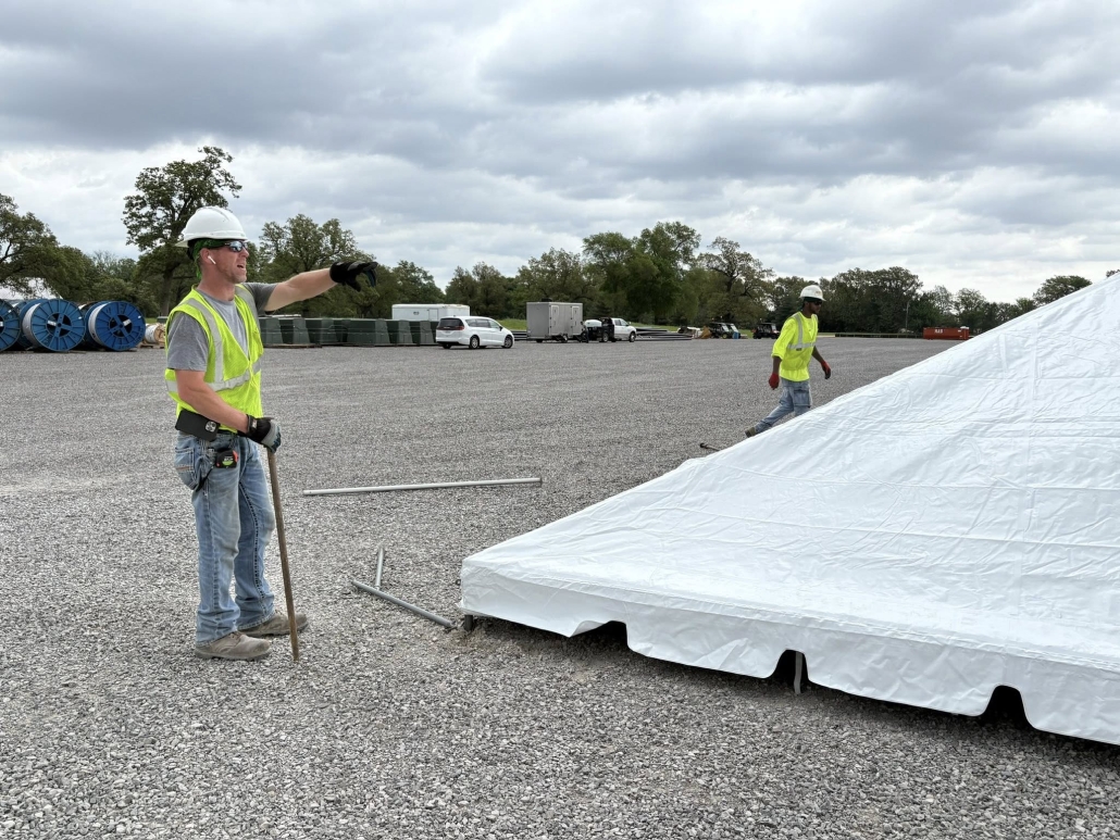 Crew in high visibility safety gear setting up an event tent.